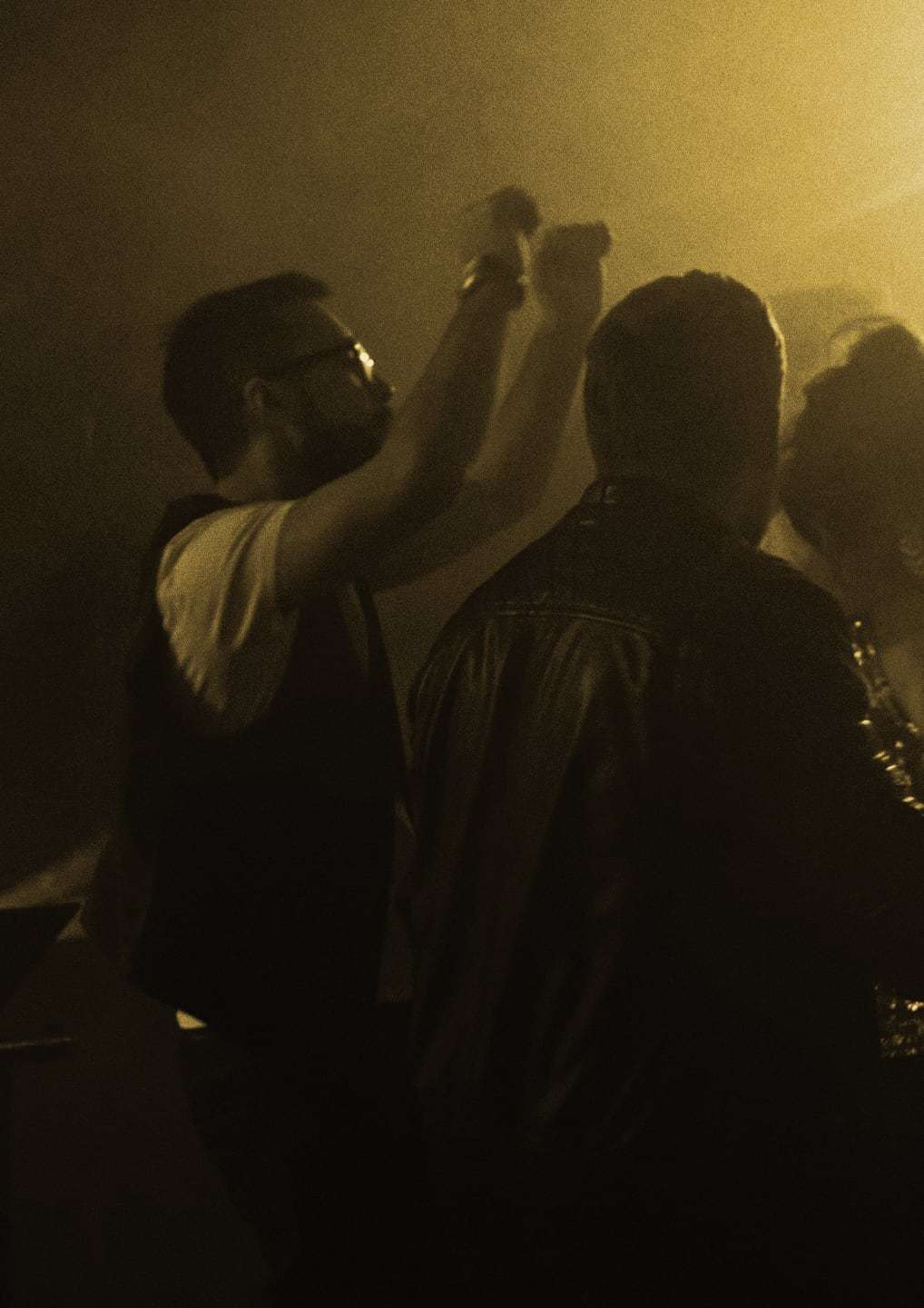 Sisli, sıcak ışıklı pistte DJ masasının yanında dans eden bir grup